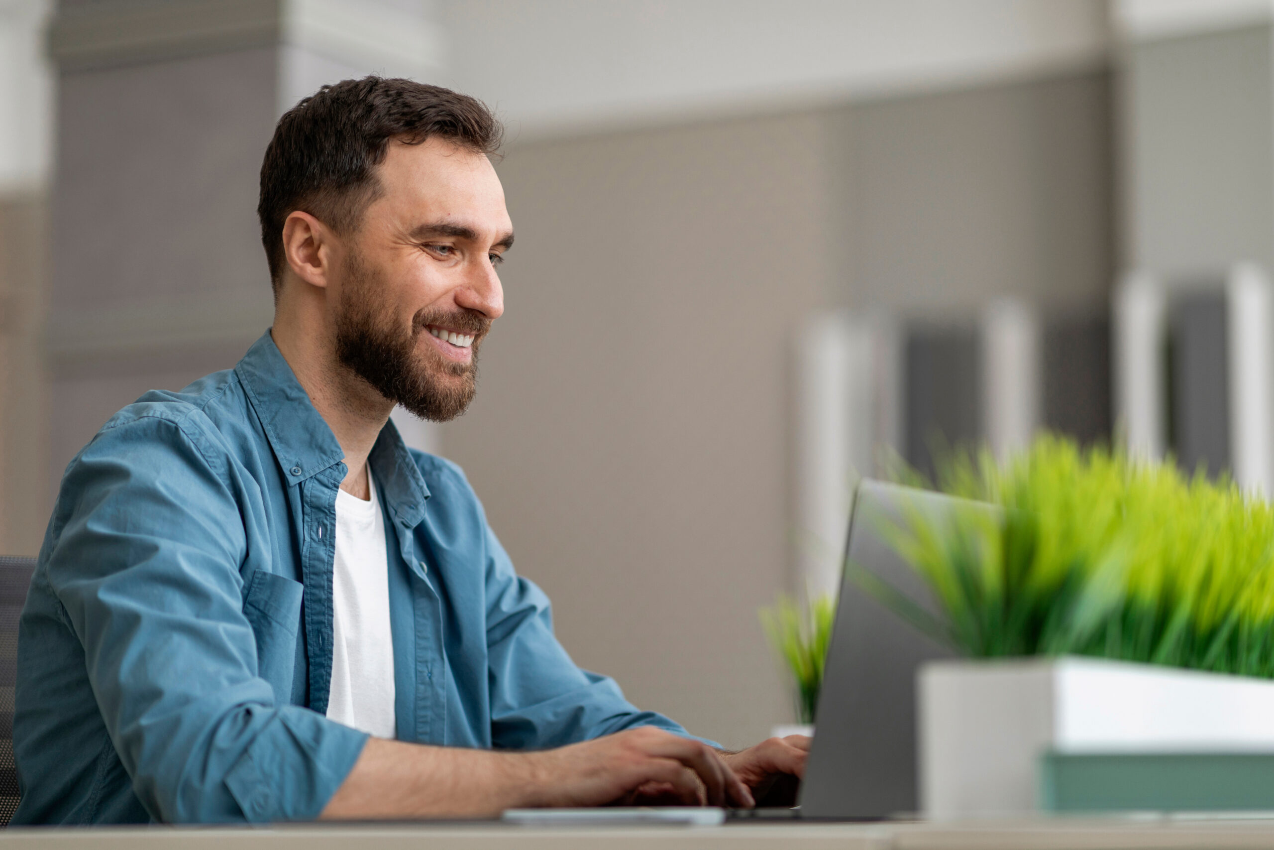 Young Man Typing At Desk in Office